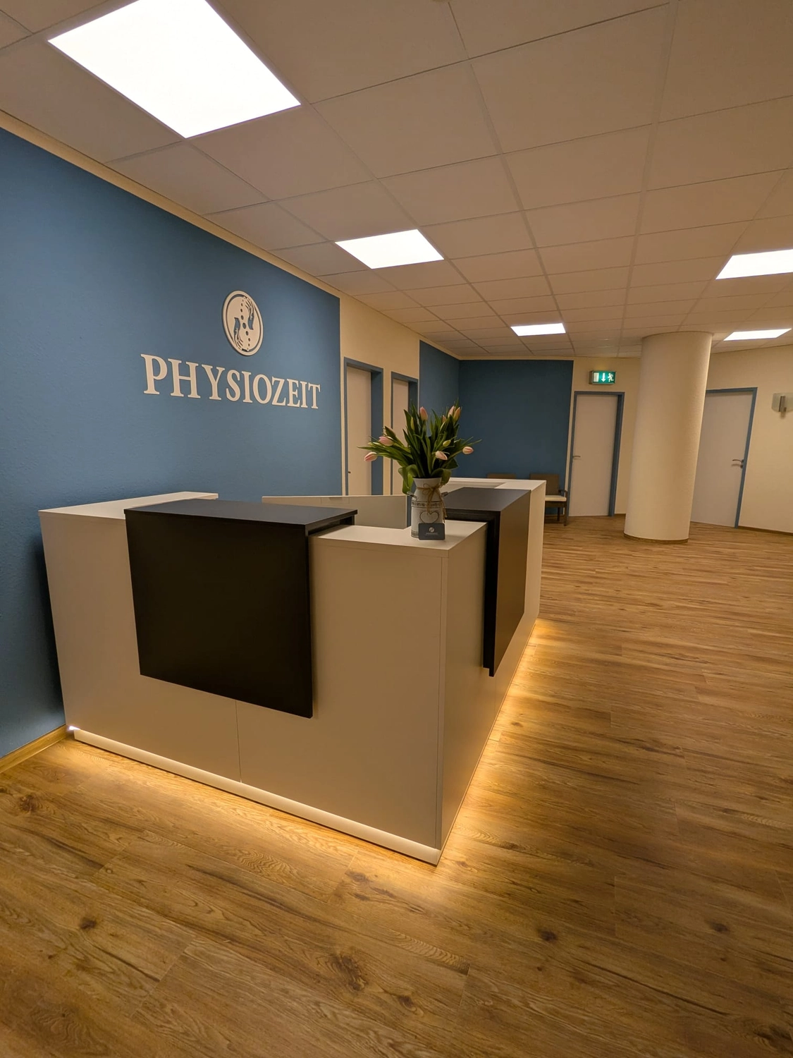 PHYSIOZEIT GbR -  physiotherapeutischen Behandlungen - Ein moderner Büroempfangsbereich mit Schreibtisch und Pflanze.